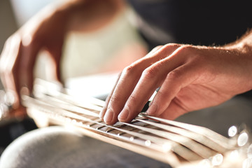 Feeling my instrument...Close-up of male hands touching metal strings of guitar