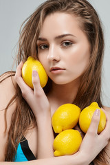 Beauty Spa Woman with perfect skin Portrait. Young woman in yellow sunglasses holding lemon .