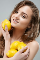 Smile young woman in yellow sunglasses holding lemons near head. Healthy Lifestyle. Beautiful Spa Woman Smiling. Perfect Fresh Skin.