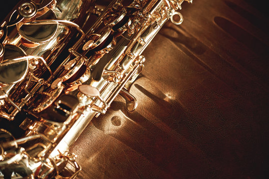Close up and detailed view of a shiny keys of a golden saxophone lying on leather sofa. Musical instruments.