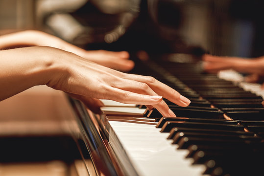 Favorite classical music...Close up view of gentle female hands playing a melody on piano while taking piano lessons