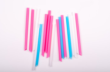Colorful big plastic straws top view on a white background used as an accent . Earth movement, plastic recycling and refuge theme. Blue,pink,white color. Beyond Plastic.