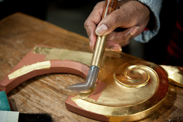 Craftsman uses agate stone for the burnish process. Gilding tecnique.