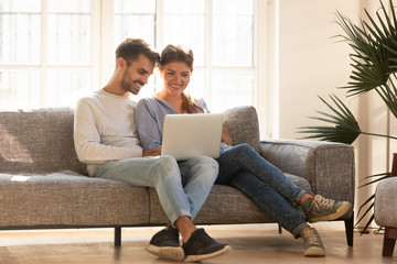 Millennial happy couple using laptop doing online shopping, ecommerce