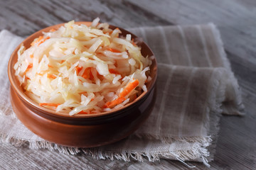 Homemade sauerkraut in a clay plate on wooden background