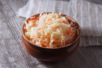 Homemade sauerkraut in a clay plate on wooden background