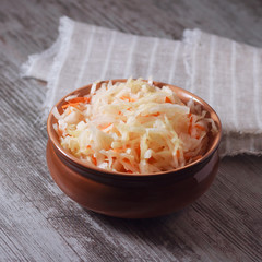 Homemade sauerkraut in a clay plate on wooden background