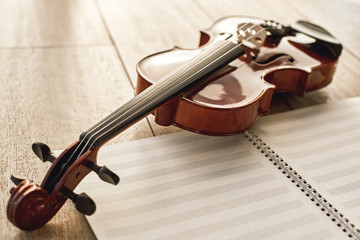 Fototapeta na wymiar Visual beauty of classical instrument. Close up view of brown beautiful violin lying on sheets for music notes over wooden floor