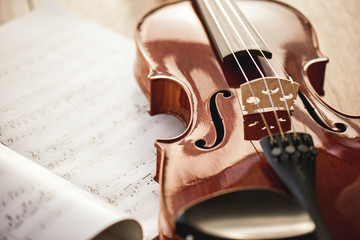 Beauty of musical instruments. Close up view of brown violin lying on sheets with music notes on...