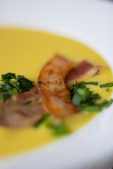 Macro pea soup with pieces of bacon, parsley and onion in a bowl on a dark background. Pea cream soup.