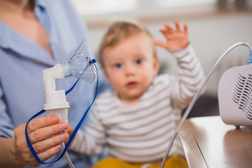 close up of nebuliser inhalation mask with baby boy in blurred background