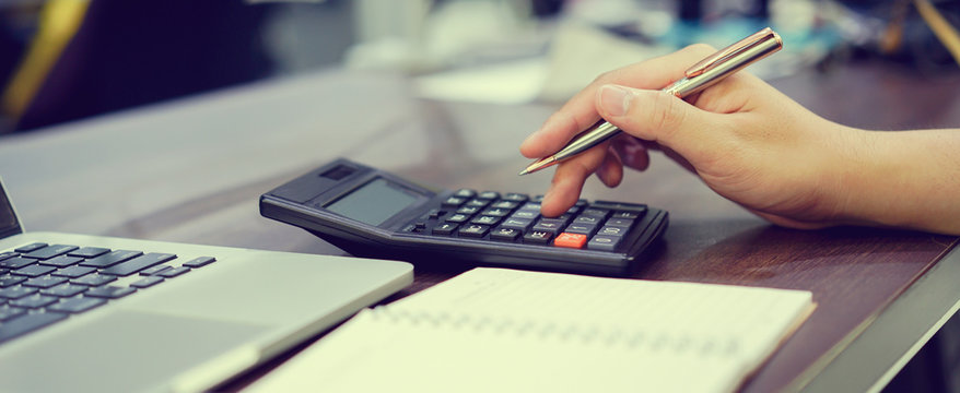 close up on employee man finger hand press on calculator for summarize company's profit at accounting department ,working man concept.	 	