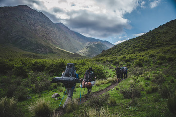 A group of people walk among green mountains.