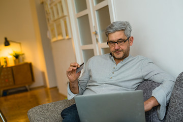 middle aged man using laptop for online shopping from his apartment