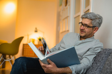 man reading book at his apartment