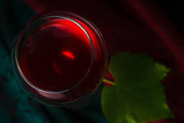 A glass of red wine on a dark velvet-green background