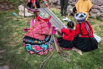 Foto op Canvas Several Peruvian women weaving a long striped textile © Terri