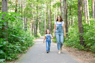 Family, nature, people concept - Young mother and cute daughter spend time together on a walk in the forest