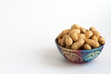 raw peanuts in shell in clay bowl on white background, copy space for text