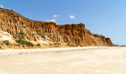 Fototapeta na wymiar High cliffs along Falesia Beach and The Atlantic Ocean in Albufeira, Algarve, Portugal. Sunny summer day, blue sky.