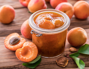 Apricot jam and ripe apricots on the table.