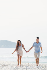 A Latin couple on vacation holding hands on the beach