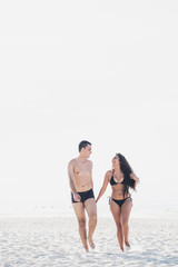 A Latin couple on vacation running on the beach