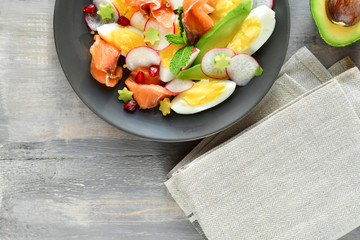 Salad with avocado and with salmon, eggs and radish. Decorated with mint leaf and pomegranate....