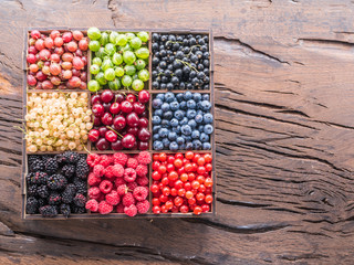 Colorful berries in wooden box on the table. Top view.