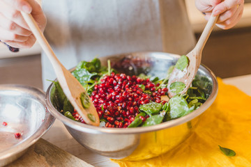 Housewife mixes salad in a large bowl with two wooden spoons