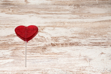 Red heart lollipop on rustic background with copy space.