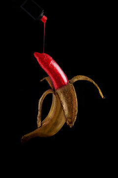 Gold banana with dripping red paint on black background
