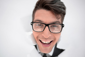 young businessman breaking through a white paper wall