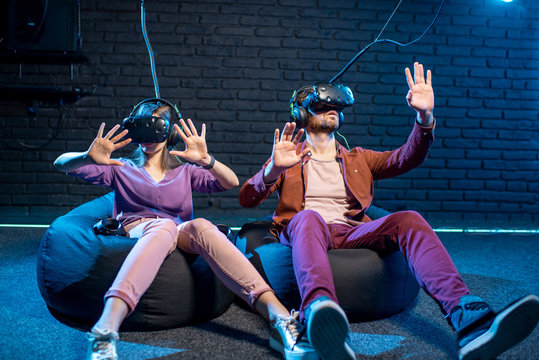 Man and woman touching space while playing in virtual reality using VR headsets in the playing room
