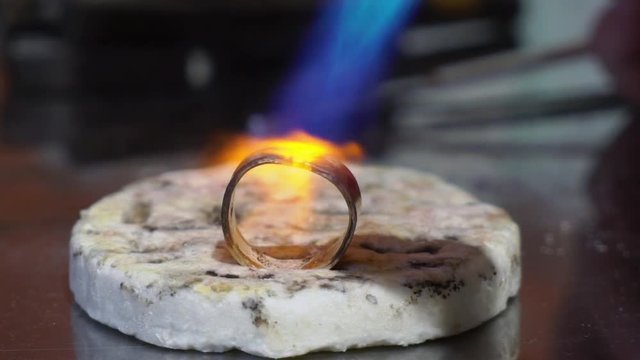 Jeweler makes a piece of jewelry - golden wedding ring