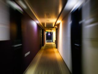 Long empty dark corridor with many doors in vintage style, toned. Motion blur effect 