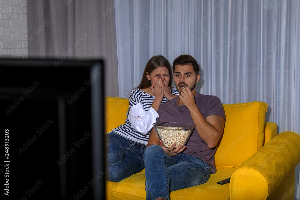 Canvas Prints Couple with popcorn watching TV together on sofa in living room