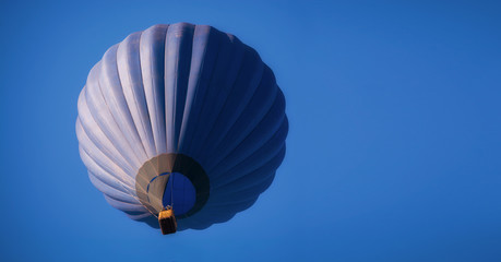 Fototapeta premium Dark blue balloon in the sky. Aerostat. People in the basket. Fun. Summer entertainment. Romantic adventures.
