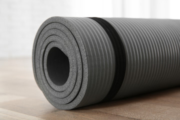 Rolled grey yoga mat on floor indoors