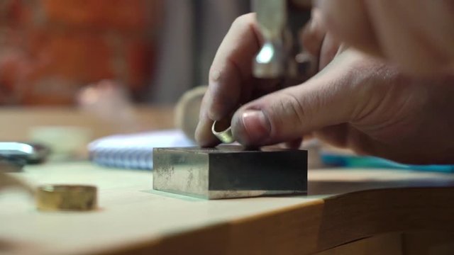 Jeweler makes a piece of jewelry - golden wedding ring