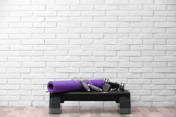Set of fitness equipment on floor near brick wall. Space for text