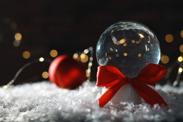 Christmas glass globe with artificial snow on blurred background. Space for text
