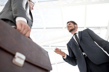 Unrecognizable businessman with suitcase close-up on a modern building background