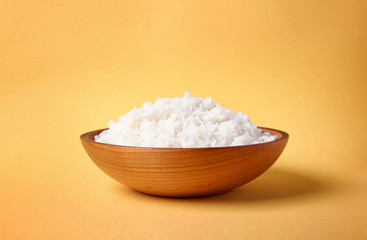 Bowl of boiled rice on color background