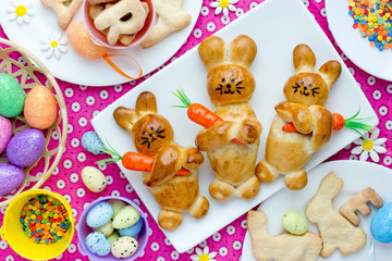 Funny Easter treats for kids -  bunny buns, bunny cookies and Easter eggs on festive table top view