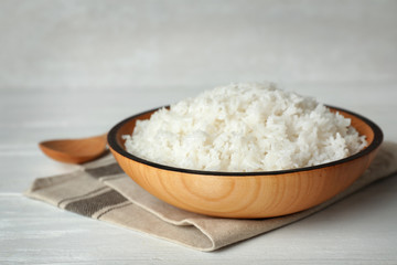 Bowl of boiled rice and spoon on wooden table