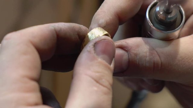 Jeweler makes a piece of jewelry - golden wedding ring