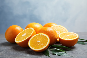 Fototapeta na wymiar Fresh oranges with leaves on grey table
