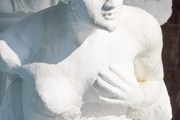 stone statue of a semi-nude woman holding her breast with her hand, breast cancer concept