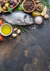 Raw dorado fish with spices and vegetables on the graphite board.